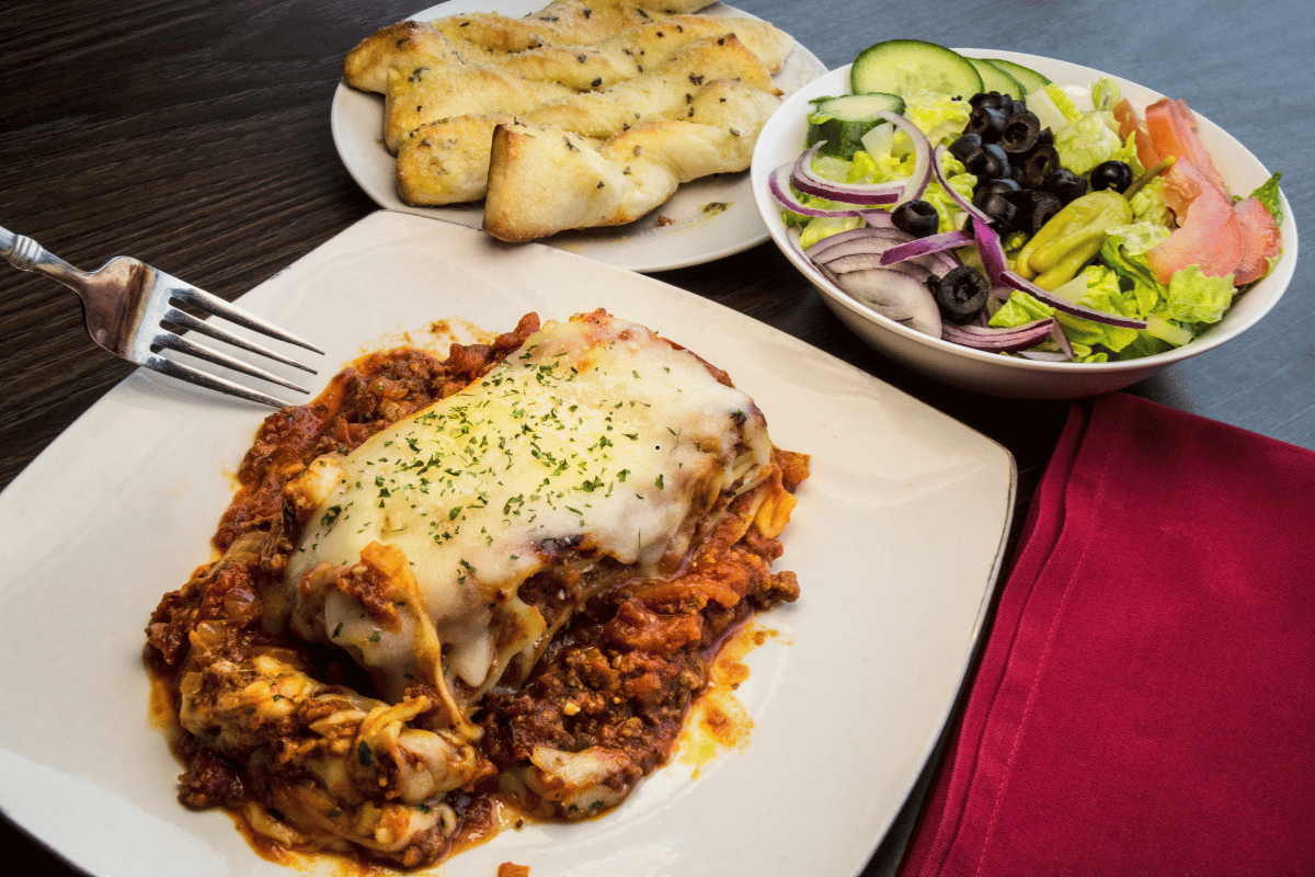 Homemade lasagna served with garlic bread and salad