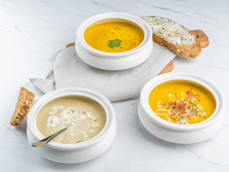 Assorted homemade fall soup recipes served with bread on a rustic table