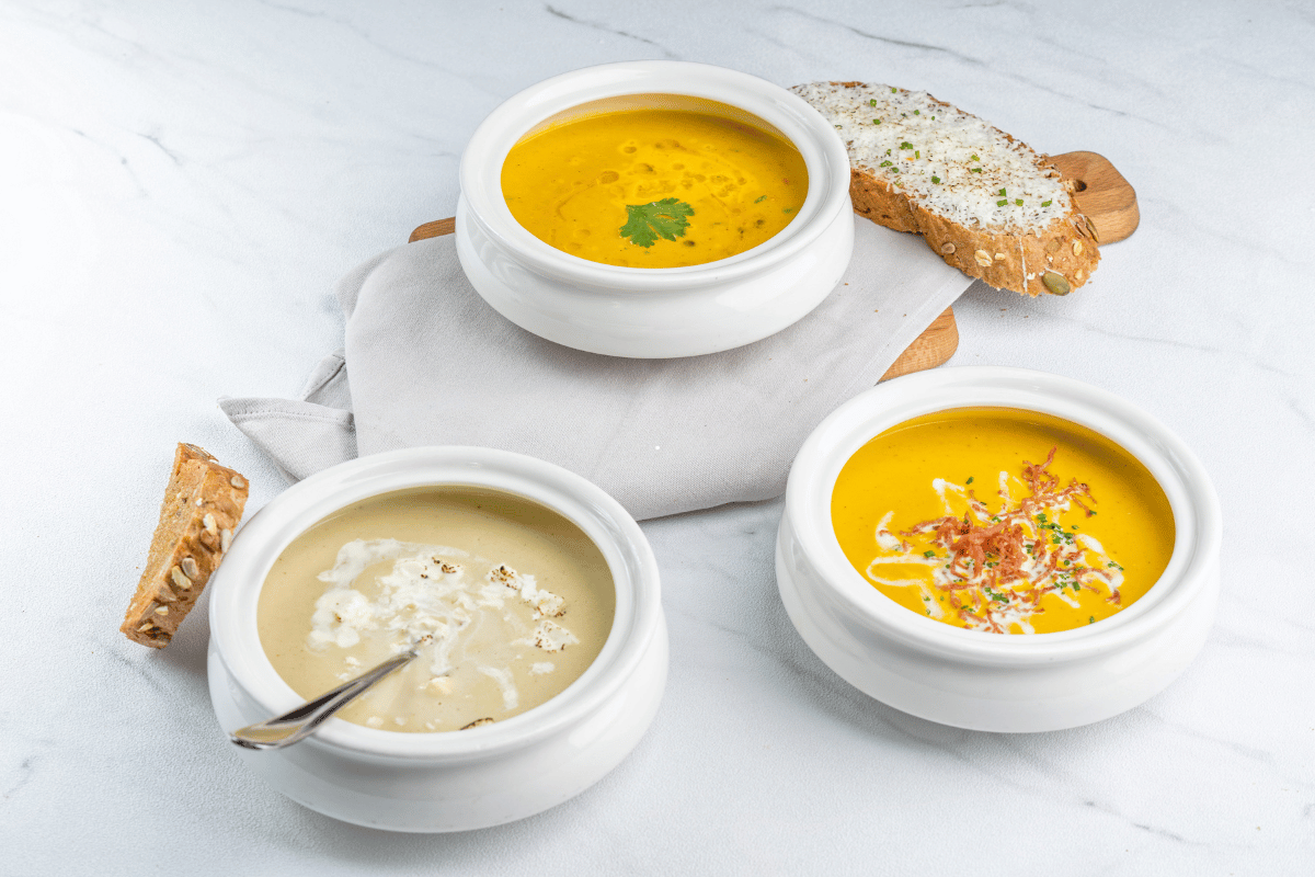 Assorted homemade fall soup recipes served with bread on a rustic table