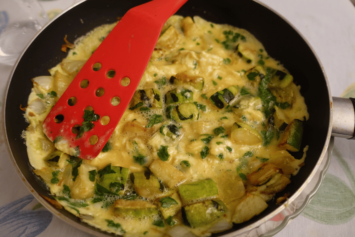 Cooking a fluffy vegetable omelet in a frying pan