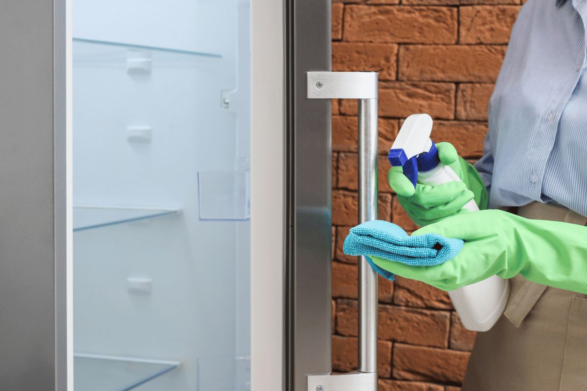Wiping refrigerator shelves with a microfiber cloth