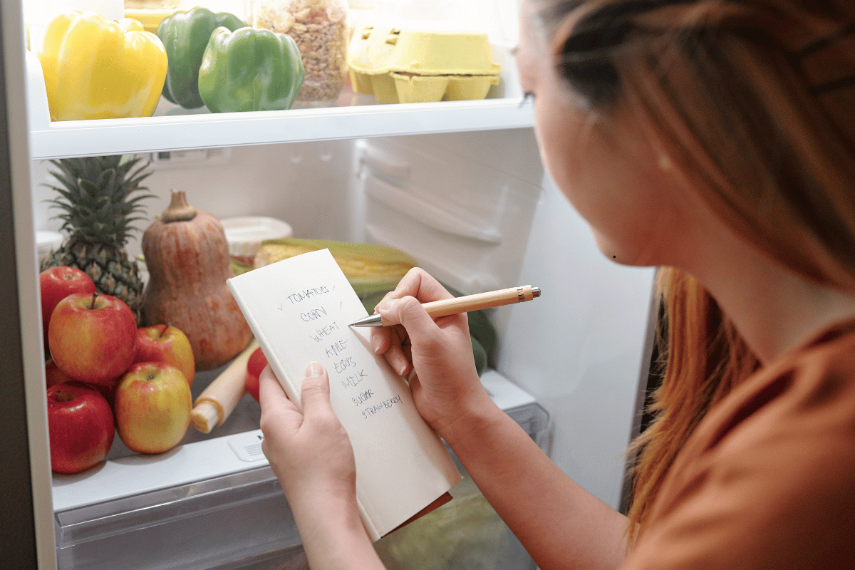 Person planning meals and writing a grocery shopping list before going to the store.