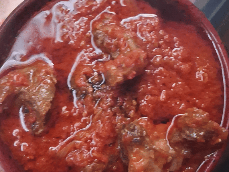 Budget-friendly Nigerian fresh tomato stew with tender goat meat served on a plate.