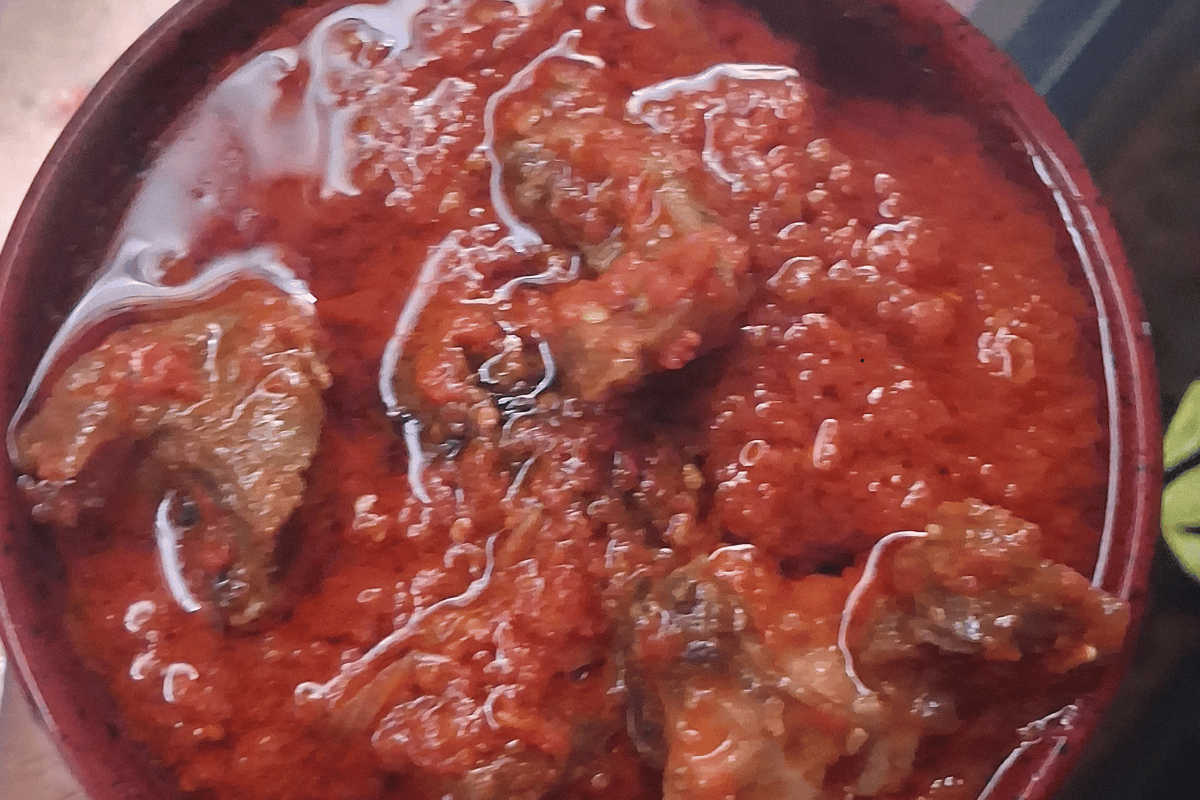 Budget-friendly Nigerian fresh tomato stew with tender goat meat served on a plate.