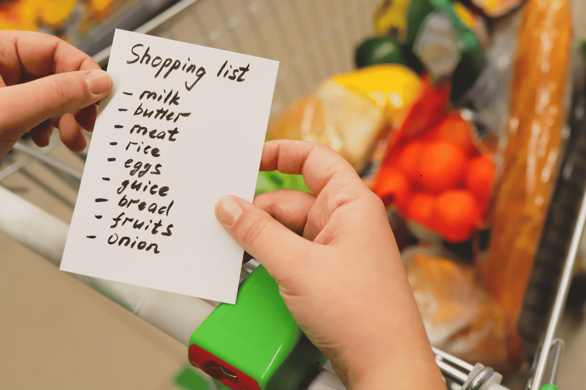 Person shopping in a supermarket while following a grocery shopping list.