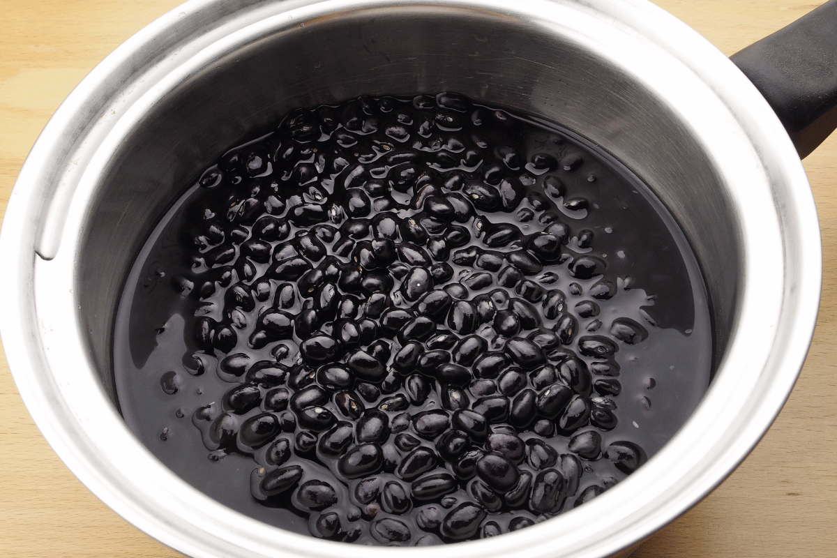 Black beans warming with cumin and garlic in a saucepan for chicken rice bowl