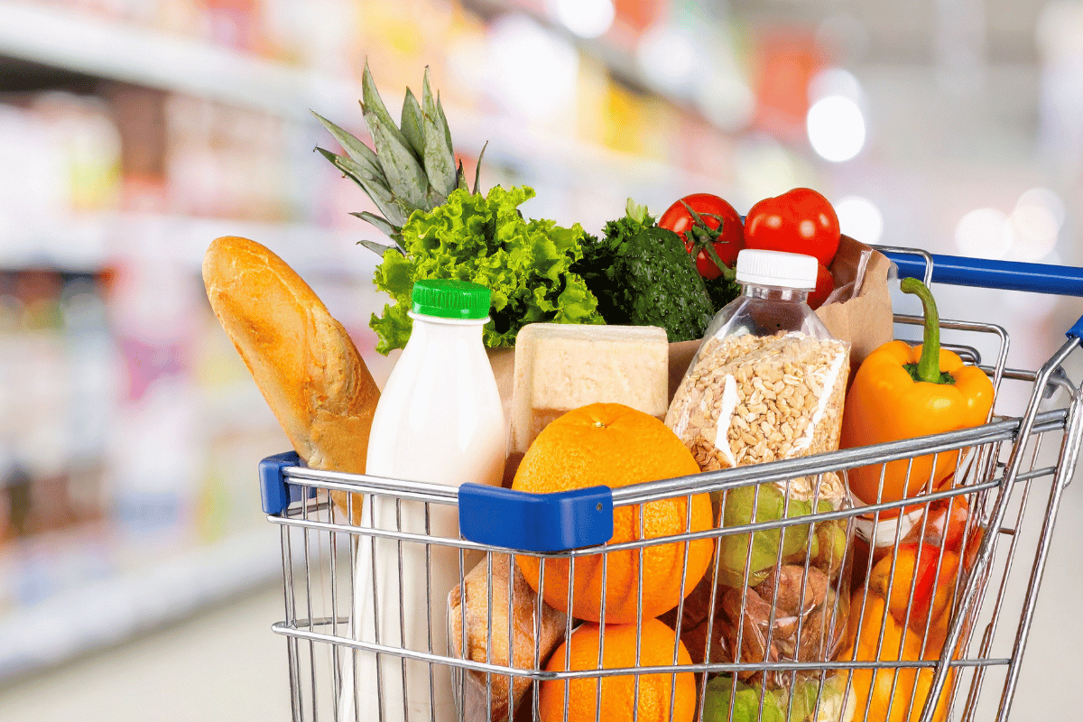 Woman grocery shopping on a budget with fresh fruits, vegetables, and healthy foods in her cart.