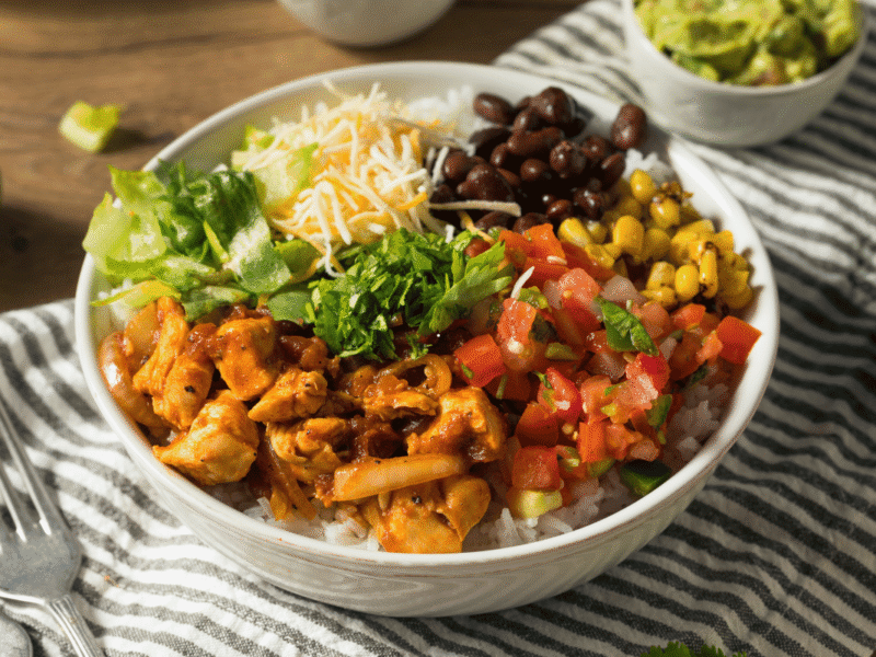 Chicken and black bean bowl with rice, avocado, corn, tomatoes and seasoned chicken