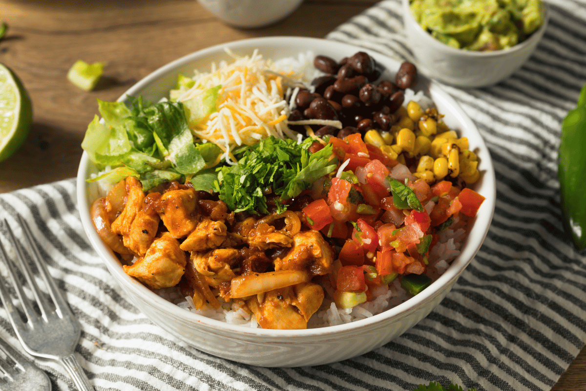Chicken and black bean bowl with rice, avocado, corn, tomatoes and seasoned chicken
