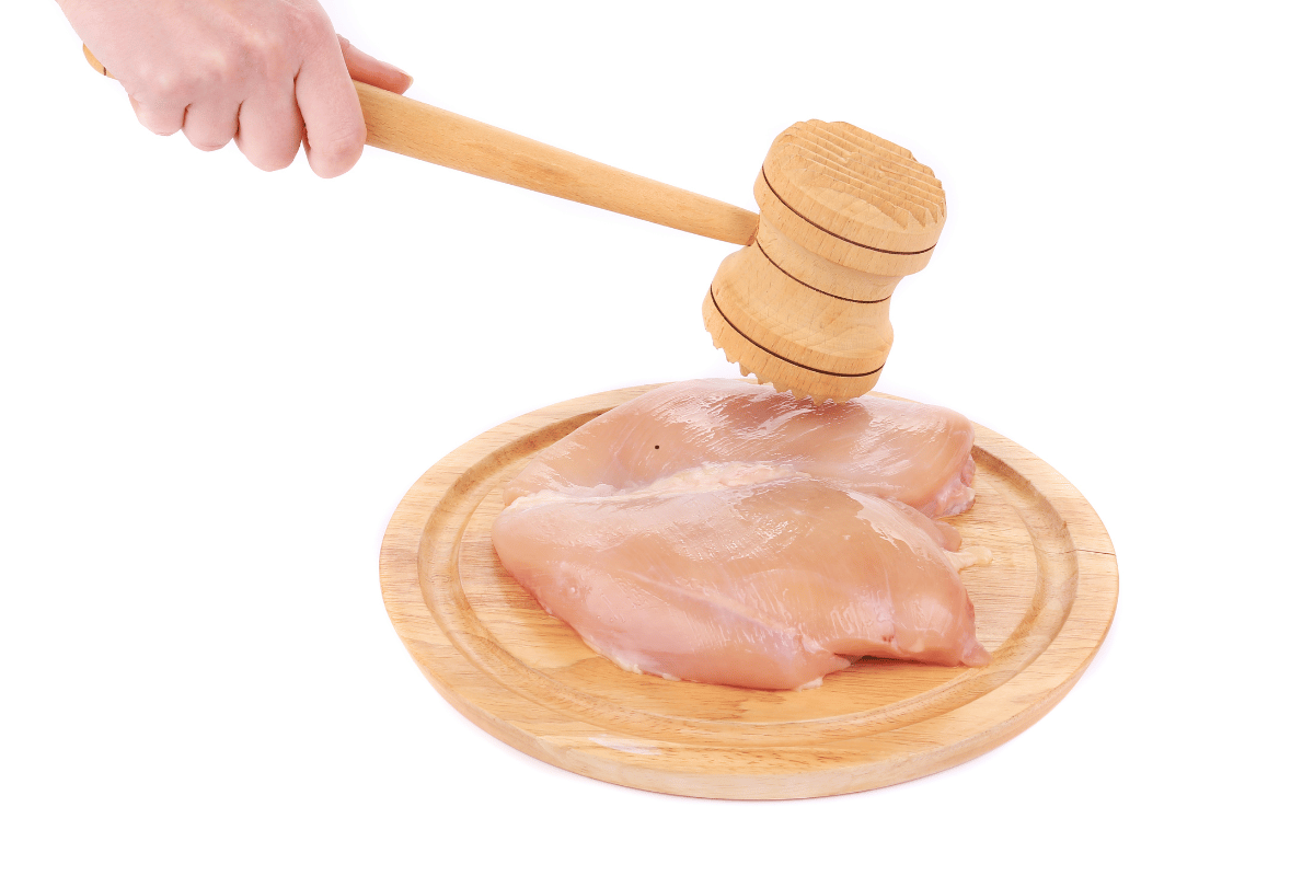 chicken breast being flattened with a meat mallet