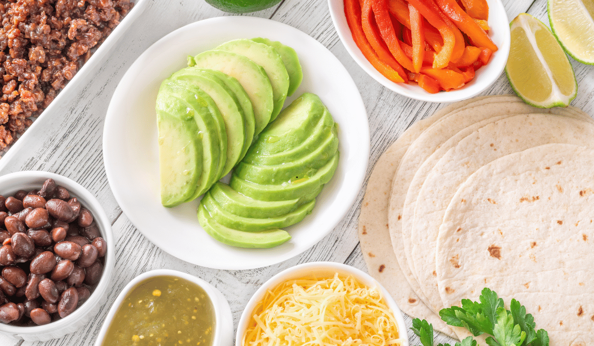 ingredients for crockpot chicken tacos with tortillas avocado lime and toppings