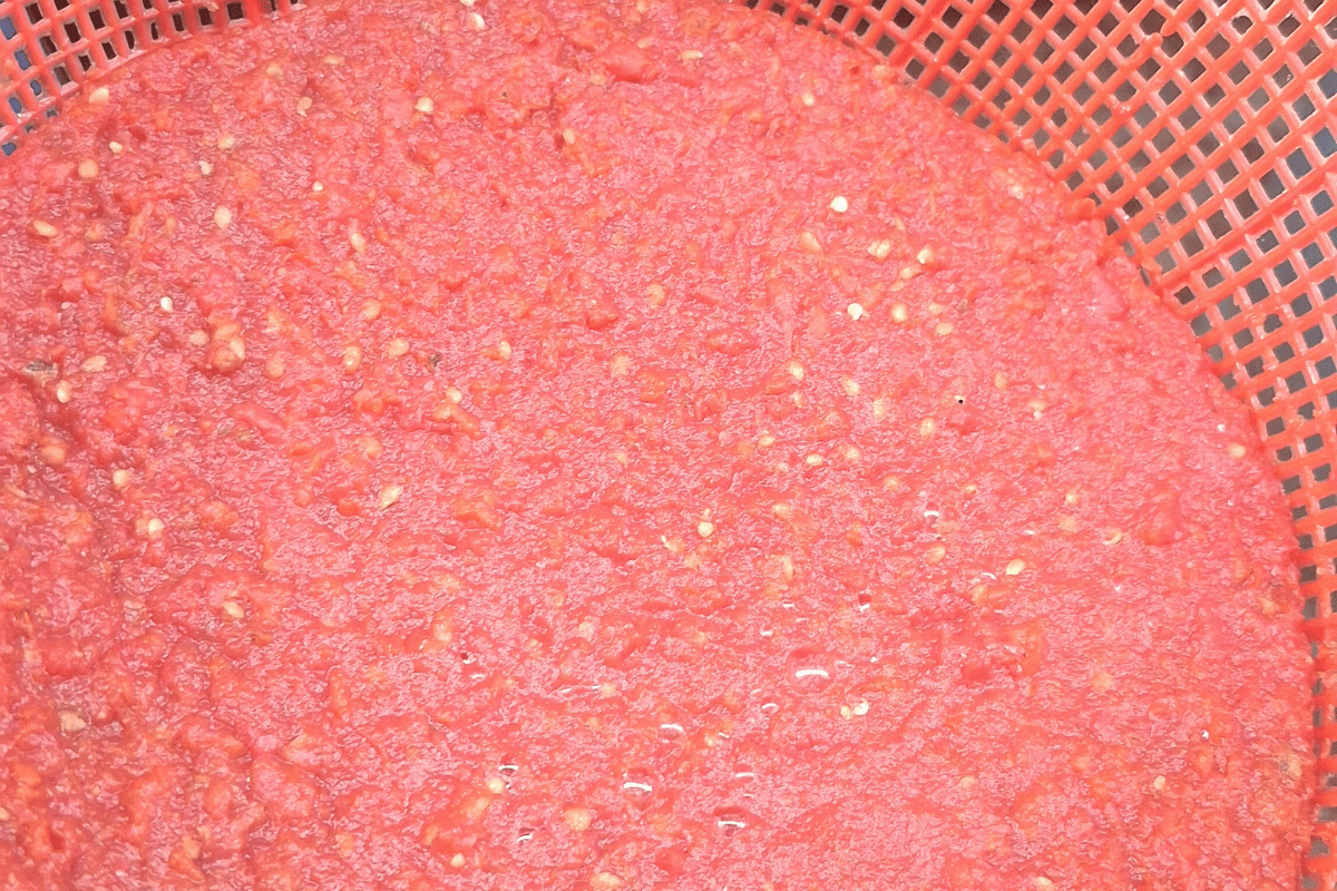 Blended tomato mixture being strained for a budget-friendly Nigerian fresh tomato stew recipe.